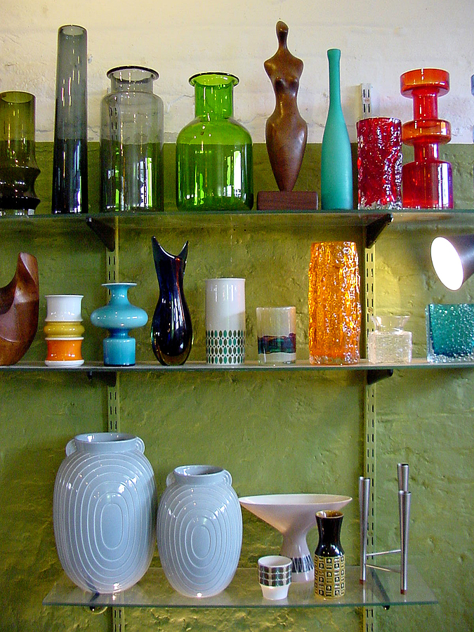 Colorful miscellany of variously shaped vintage vases in glass and ceramics on display in an antiques store